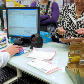 Unos pensionistas retiran sus medicamentos y pagan su aportación corespondiente al sistema de copago. EFE/Villar López