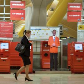 Una mujer pasa junto a los terminales de facturación de Iberia en la Terminal T4 del aeropuerto de Barajas. AFP/Pedro Armestre