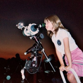 Niña mirando por un telescopio.