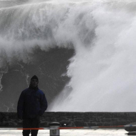 Un hombre camina cerca de las olas esta tarde en la costa de Muxía (A Coruña). | LAVANDEIRA JR. (EFE)