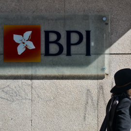 Una mujer pasa junto a una oficina del banco BPI en Lisboa.  AFP / Patricia de Melo Moreira