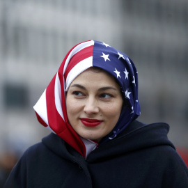 Una mujer musulmana con un velo con la bandera de Estados Unidos en la concentración contra Trump en Berlín / REUTERS