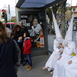 Unos nazarenos descansan en una parada de autobús en Sevilla. REUTERS/Marcelo del Pozo