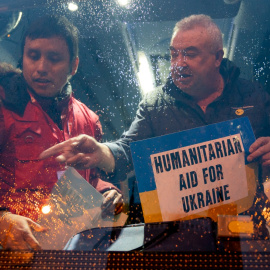  Dos personas colocan el cartel de ayuda para Ucrania en uno de los autobuses del convoy de la Fundación Madrina, en la plaza de San Amaro, a 11 de marzo de 2022, en Madrid (España).- A. Pérez Meca / Europa Press