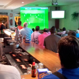 Clientes de un bar viendo un partido de fútbol por televisión.