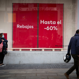 5/1/22-Varias personas pasan delante de un escaparate con cartel de rebajas en una calle comercial del centro de Madrid, a 2 de enero de 2022, en Madrid, (España).