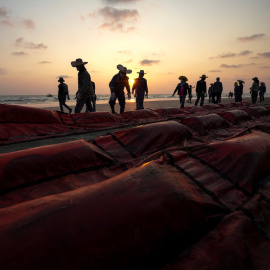 Un grupo de trabajadores trata de bloquear el derrame de petróleo causado ​​por una fuga de un oleoducto submarino a 20 km de la costa este de Tailandia en la playa de Mae Ramphueng, provincia de Rayong, a 28 de enero de 2022.