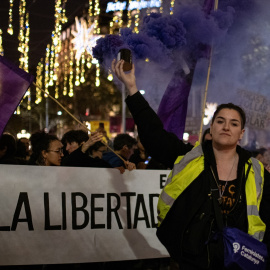 Una mujer con un bote de humo morado, durante una manifestación por el 25N en Barcelona.