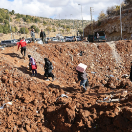 Personas que huyen de los bombardeos israelíes en Líbano cruzan un cráter, causado por un ataque israelí, en el área de Masnaa, en el lado libanés del cruce fronterizo con Siria, el 20 de noviembre de 2024