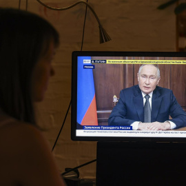 Una mujer mira un discurso televisado del presidente ruso Vladimir Putin, en Moscú, Rusia.