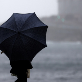 Una persona con paraguas se protege de la lluvia, en una imagen de archivo.