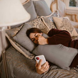  Una mujer en el sofá con su teléfono móvil.- RDNE Stock project.