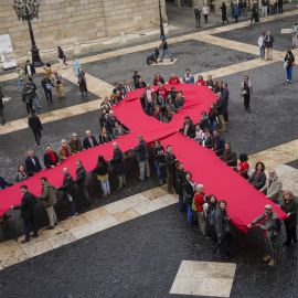 Un lazo memorial del Sida de despliega en la plaza Sant Jaume este domingo, en el que se celebra el Día Mundial del Sida. EFE/Enric Fontcuberta