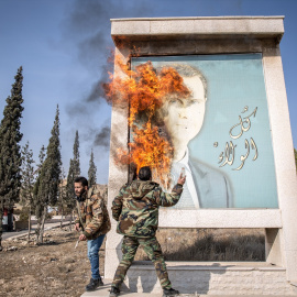 Dos hombres queman una imagen de Al Asad en Damasco.