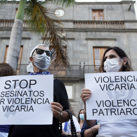 Dos personas con carteles contra la violencia vicaria en una protesta contra la violencia machista.