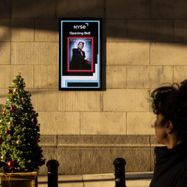 Una persona pasa junto a una pantalla con una imagen del presidente electo de Estados Unidos, Donald Trump, en el exterior de la Bolsa de Nueva York (EE.UU.).