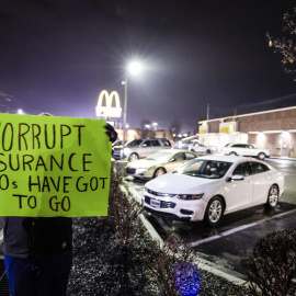 Una mujer que no quiso ser identificada y que trabaja en el sector de la salud sostiene un cartel de protesta frente al restaurante McDonald's donde el Departamento de Policía de Altoona arrestó a Luigi Mangione, el sospechoso del asesinato Brian Thompson, CEO de UnitedHealthcare.