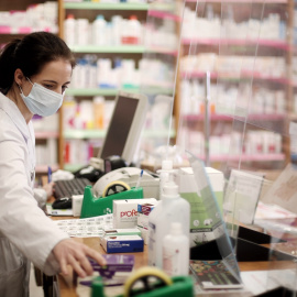 Una farmacéutica con mascarilla despacha en una farmacia de Madrid, en una imagen de archivo.