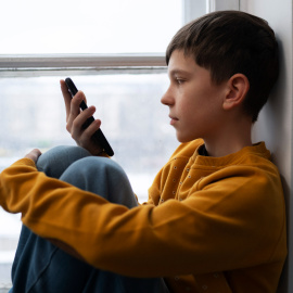 Niño solo con teléfono móvil.