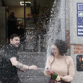 Beatriz Rodríguez, dueña de la administración de San Sebastián de los Reyes que ha vendido parte del número 06.766 agraciado con el segundo premio, abre una botella para celebrarlo.