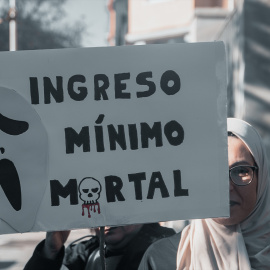 Una mujer sujeta un cartel de protesta durante una concentración convocada por la plataforma RMI Tu Derecho (Renta Mínima de Inserción) en Madrid el pasado 28 de diciembre de 2024.