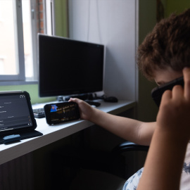 Un niño usa el teléfono móvil y una tablet