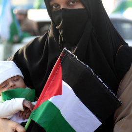 Una mujer sostiene a un bebé y una bandera palestina mientras los partidarios del partido político islámico Jamaat-e-Islami marchan para expresar solidaridad con el pueblo palestino, en Karachi, Pakistán.