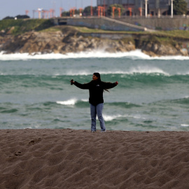 Una mujer caminando por la playa de Riazor, en A Coruña, a la espera de la llegada de la borrasca Herminia, a 25 de enero de 2025.