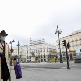 Un hombre camina protegido con mascarilla por la Puerta del Sol de Madrid prácticamente vacía.