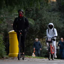 Imagen de archivo de una persona que monta en bicicleta y otra en patinete eléctrico en Barcelona.