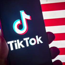 El logotipo de la aplicación de redes sociales TikTok aparece en un teléfono inteligente frente a la bandera estadounidense. Imagen de archivo.