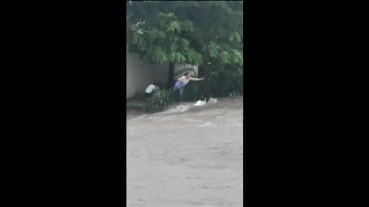 Madre e hijo son arrastrados por la corriente de una calle inundada en ...