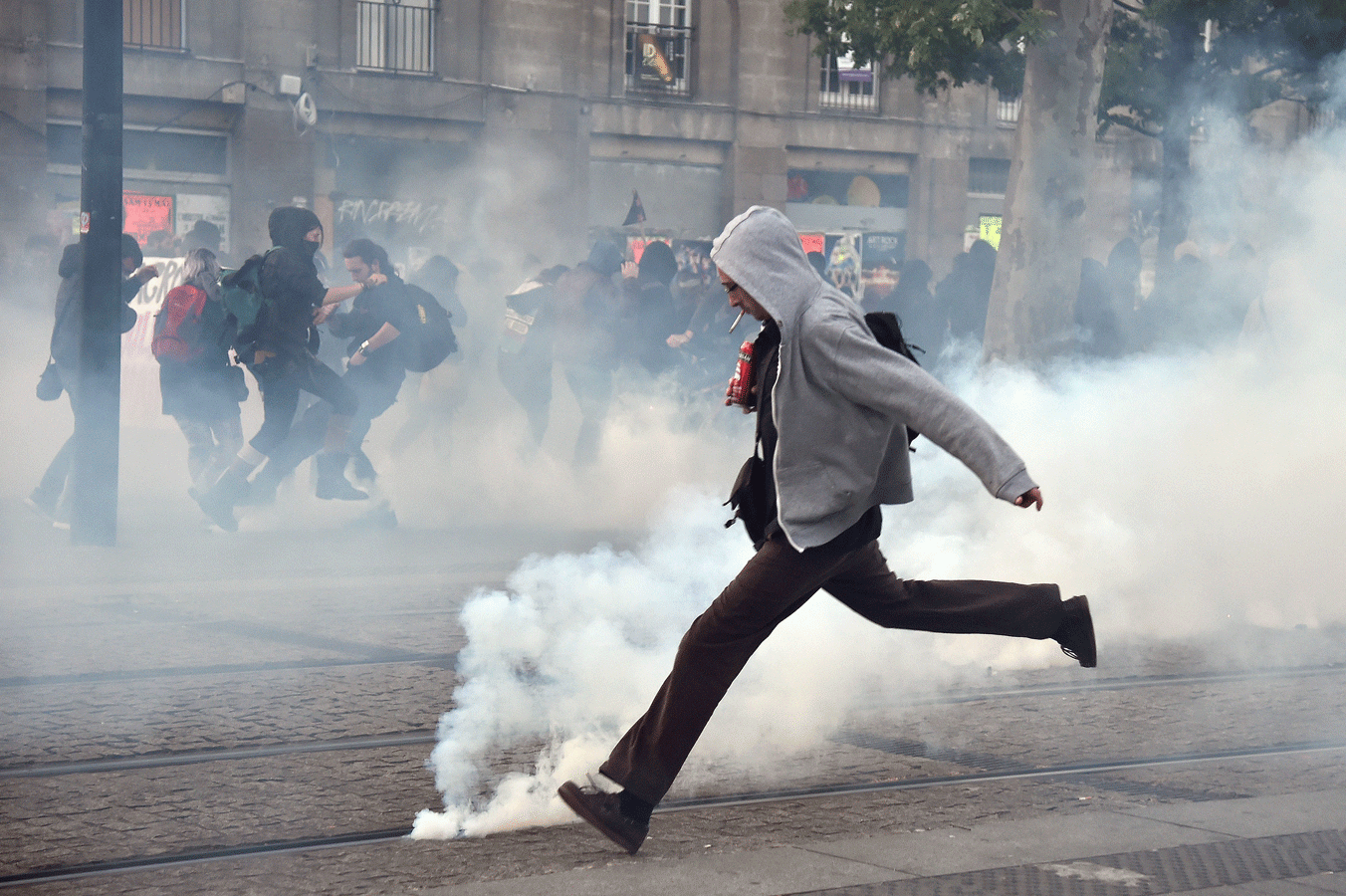 Un manifestante trata de alejar un bote de gas lacrimógeno en Nantes.- AFP